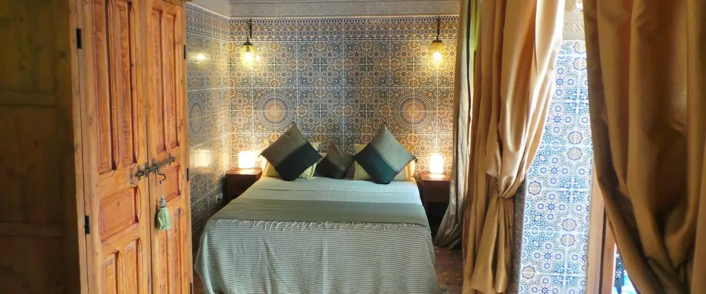 Une chambre sous un mur de zellige